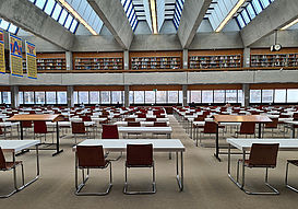 Das Bild zeigt einen Lesesaal in der Uni-Bibliothek. Man sieht einen gro?en, hellen Raum. Darin stehen viele Tische und Sthle. Im Hintergrund sieht man bwin_bwinֹӭ@nen und Studenten, die arbeiten. Man sieht auch einige Bcherregale.